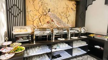 Un tavolo da buffet con diversi cibi e una parete decorata con un pavone.