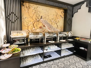 A buffet setup with various food items and a decorative wall with a peacock. - Luang Prabang Indochine Heritage Hotel (Luang Prabang)