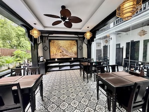 A restaurant with a traditional design, featuring a patterned floor, black and white decor, and a large mural on the wall. - Luang Prabang Indochine Heritage Hotel (Luang Prabang)