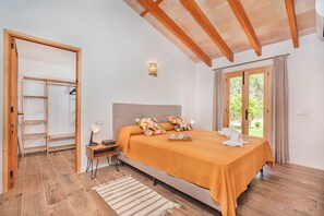 Ein Schlafzimmer mit Bett, Nachttisch, Lampe und Blick ins Freie durch ein Fenster.