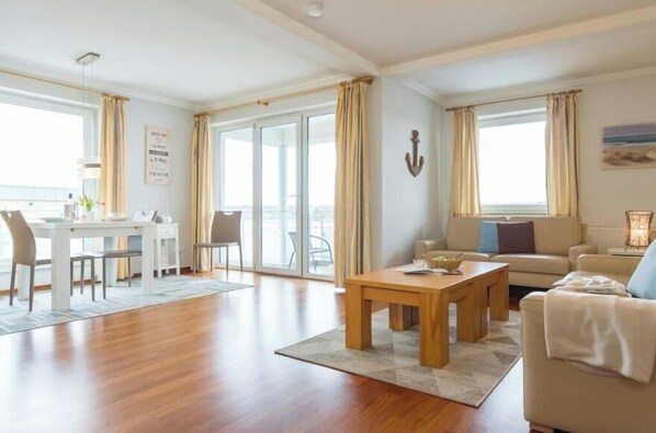 Ein geräumiges Wohnzimmer mit Essbereich, großen Fenstern und Meerblick.