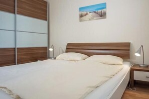 A bedroom with a bed, bedside tables, and a wall-mounted picture. - Holiday apartment with 2 bedrooms (Großenbrode)