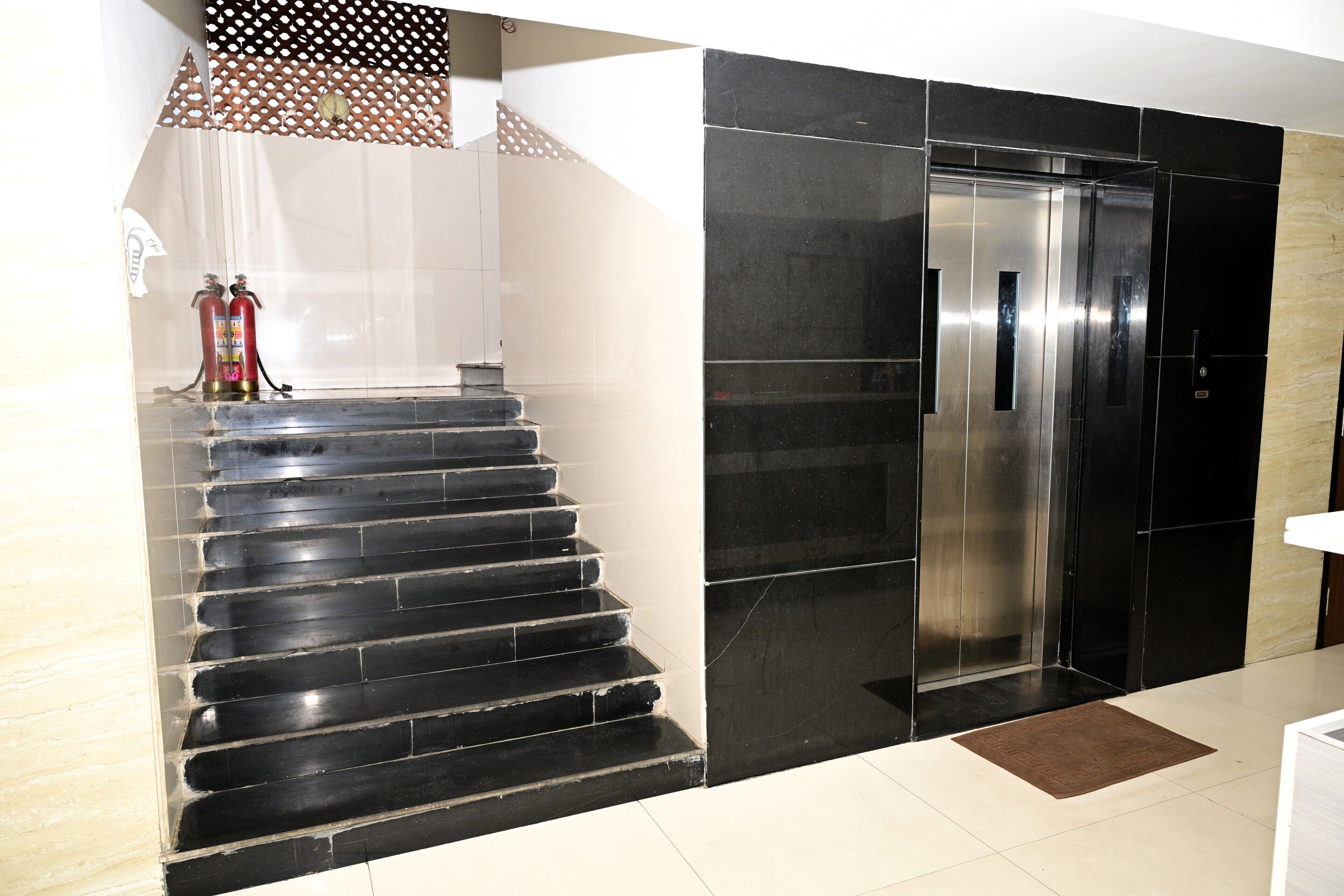 Una escalera con escalones negros que conduce a un moderno ascensor.