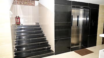 Una escalera con escalones negros que conduce a un moderno ascensor.