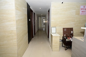 A hotel reception area with a reception desk, a security camera, and a sign indicating a room rate. - HOTEL SWAGATH INN (Vijayawada)