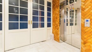 A hotel entrance with a wooden herringbone floor, double doors with glass panels, and a sign indicating a hotel.
