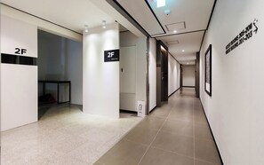 Un pasillo de hotel con un cartel que indica la habitación 2F, un piso de baldosas y un cuadro en la pared.