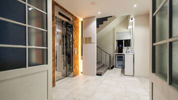 A hotel hallway with a glass door leading to guest rooms, a staircase, and a mini-fridge.