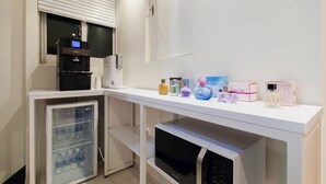A kitchenette with a refrigerator, microwave, coffee maker, and a small oven.