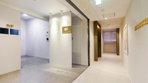 A hotel corridor with a sign indicating room 8F, a fire alarm, and a door marked 808.