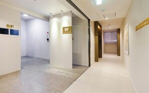 Pasillo de hotel con un cartel que indica la habitación 8F, un detector de incendios y una puerta con el número 808.