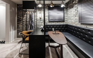 Un interior moderno con un sofá de cuero negro, una mesa de madera y una pared de ladrillo.