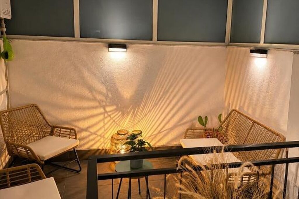 Un balcon agrémenté de meubles en osier, d’une table et d’une plante en pot.