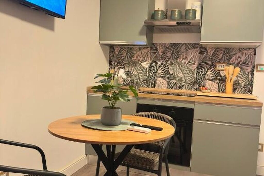 A compact kitchen with a round dining table, a potted plant, and a built-in dishwasher.