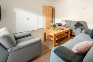 A modern living room with a grey sofa, a wooden coffee table, and a grey couch. - Schmalenbeck House Lucius 1 (Norderney)