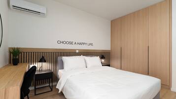 A modern bedroom with a bed, bedside tables, a desk, and a potted plant.