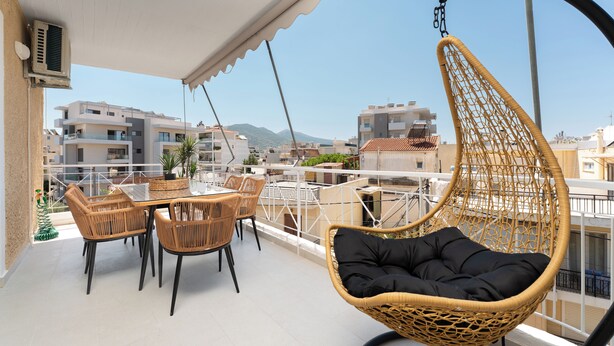 A balcony with a hanging chair, wicker chairs, and a table with chairs. - Luxury 4Bedrooms Stay in North Athens (Agia Paraskevi)