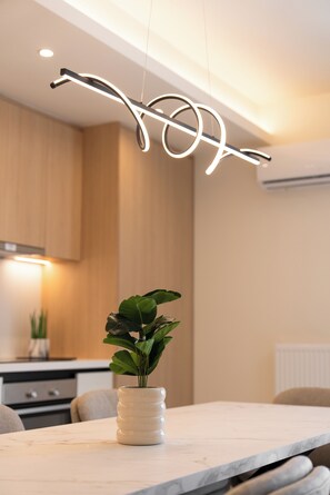 A modern dining area with a marble table, a potted plant, and a unique light fixture. - Luxury 4Bedrooms Stay in North Athens (Agia Paraskevi)