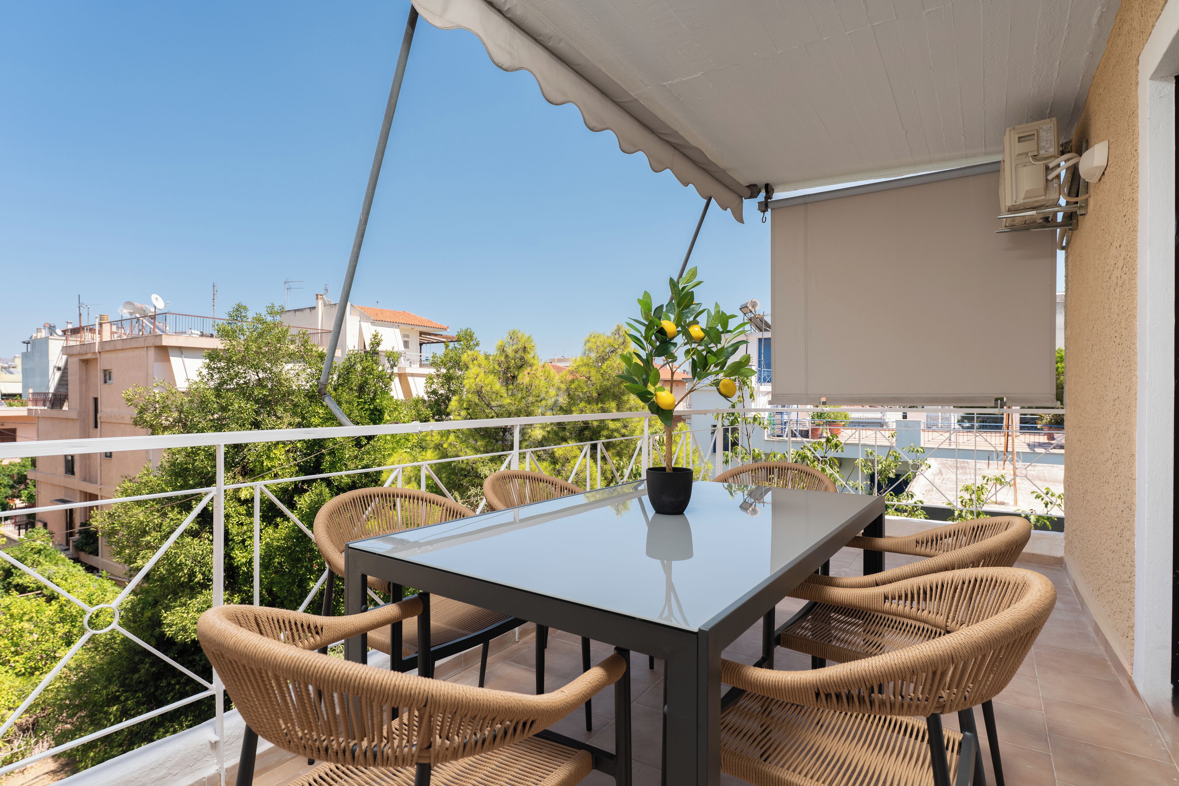 Un balcone con tavolo e sedie, una pianta in vaso e vista sulla città.