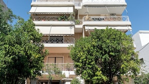 A multi-story residential building with balconies, a clear sky, and surrounding greenery. - Luxury 4Bedrooms Stay in North Athens (Agia Paraskevi)