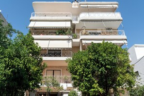 A multi-story residential building with balconies, a clear sky, and surrounding greenery. - Luxury 4Bedrooms Stay in North Athens (Agia Paraskevi)