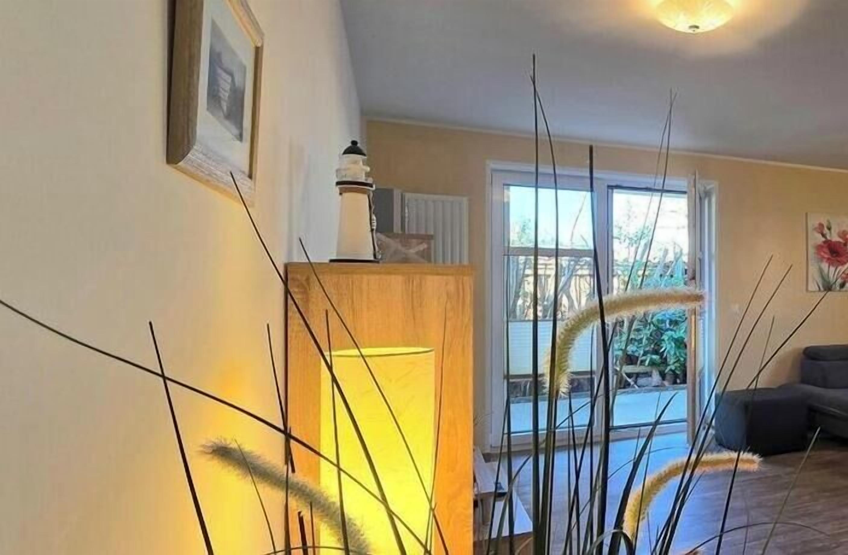 Een kamer met een raam, een lamp en een meubel.