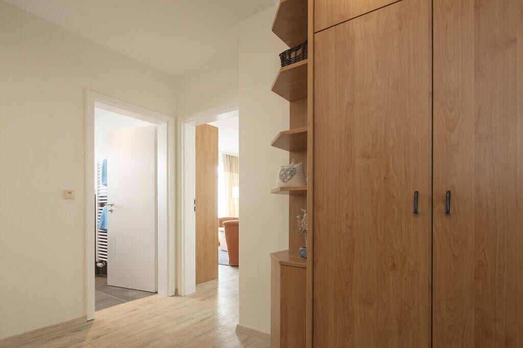 Un couloir avec des armoires en bois et une porte donnant sur une pièce équipée d’un radiateur.