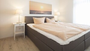 Ein Schlafzimmer mit einem Bett, zwei Nachttischen, einer Kommode und einem Wandbild.