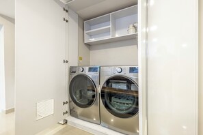 A compact laundry room with two front-loading washing machines and a small shelf above. - Cartagena Luxury House (Cartagena de Indias)