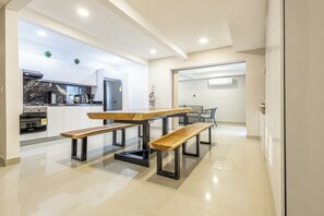A modern kitchen with a marble countertop, built-in oven, and a dining area with a wooden table and benches. - Cartagena Luxury House (Cartagena de Indias)