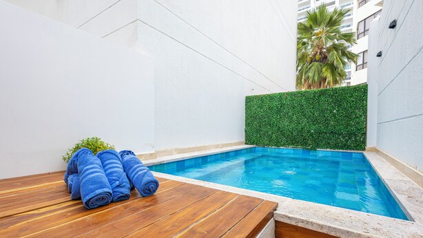Ein kleiner Pool mit einer Holzterrasse und einer Hecke.