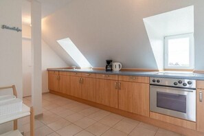 Eine Küche mit Holzausstattung, einem Edelstahlbackofen und einer Kaffeemaschine auf der Arbeitsplatte.