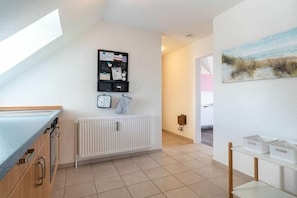 A modern kitchen with a built-in oven, a white radiator, and a breakfast bar. - 54-degree panoramic view (Sankt Peter-Ording)