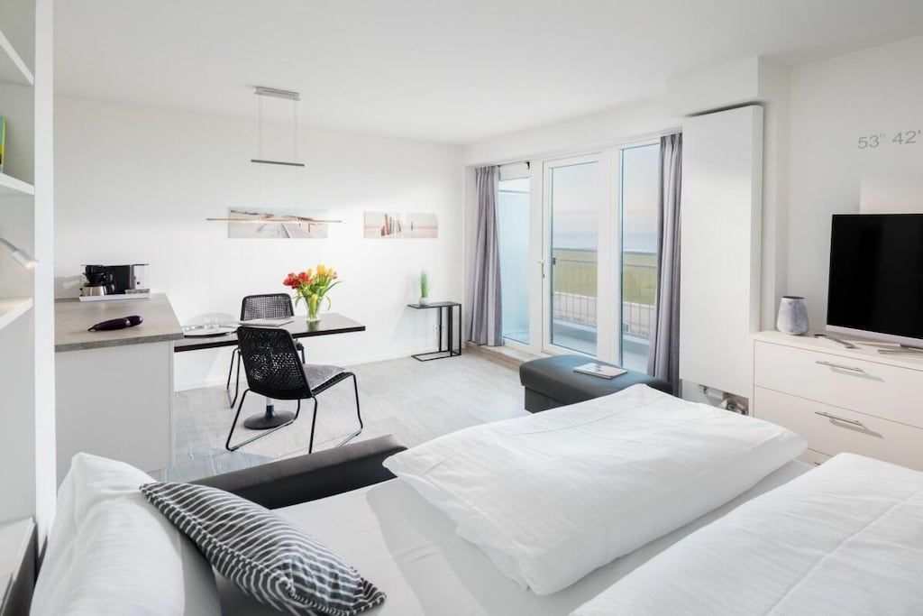 Une chambre d’hôtel avec un lit, un bureau et une chaise, une télévision et un balcon avec vue.