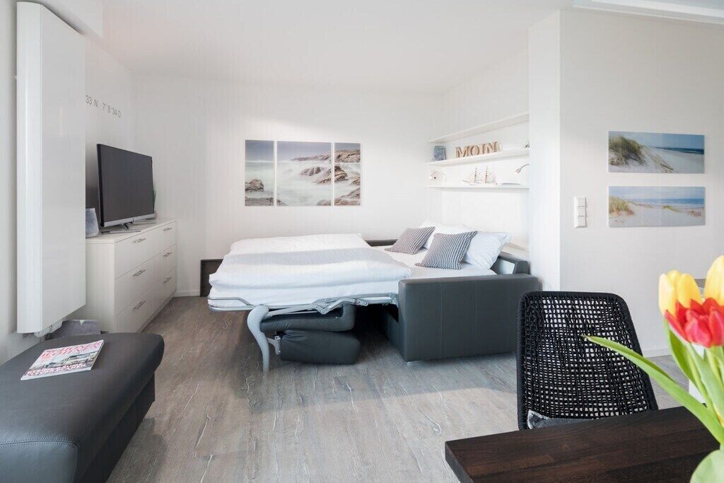 A modern hotel room with a bed, a TV, a desk, and a chair.