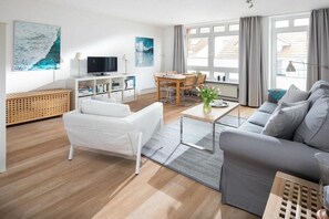 Ein modernes Wohnzimmer mit einer Couch, einem Couchtisch und einem Fernseher.