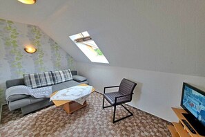 A cozy room with a sofa, a chair, a small table, a television, and a skylight. - Groth holiday apartments (Heringsdorf (Seebad))