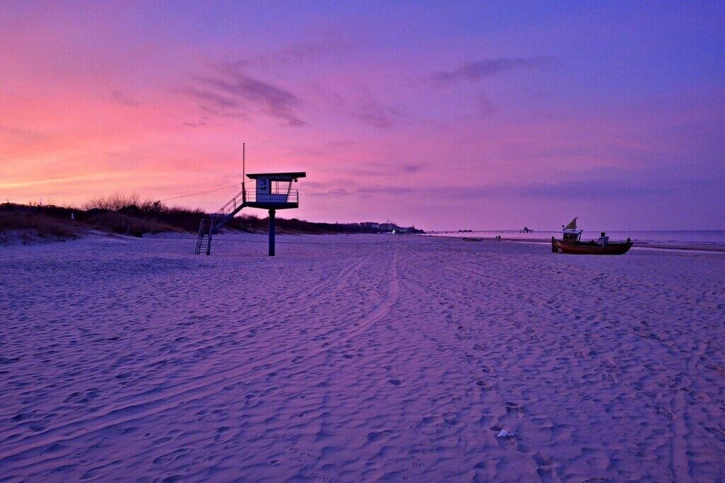 A lifeguard tower on a beach at sunset.