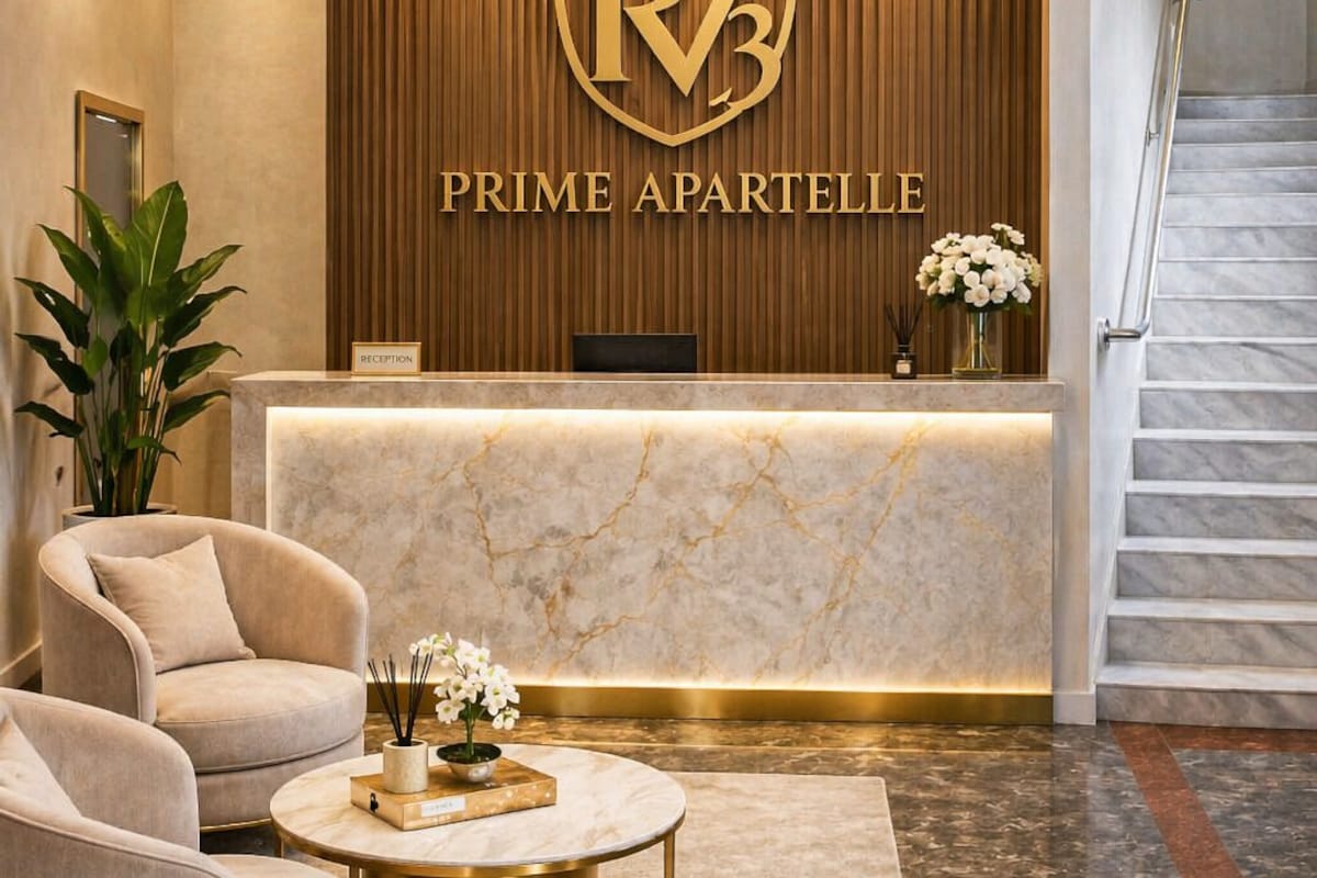 A reception area with a marble counter, a reception desk, a staircase, and two plush armchairs.