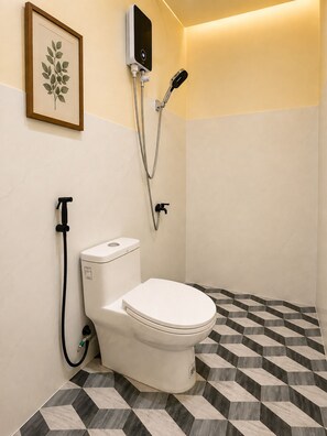 A bathroom with a toilet, a shower, and a framed plant on the wall. - RV3 Transient House (Angeles)