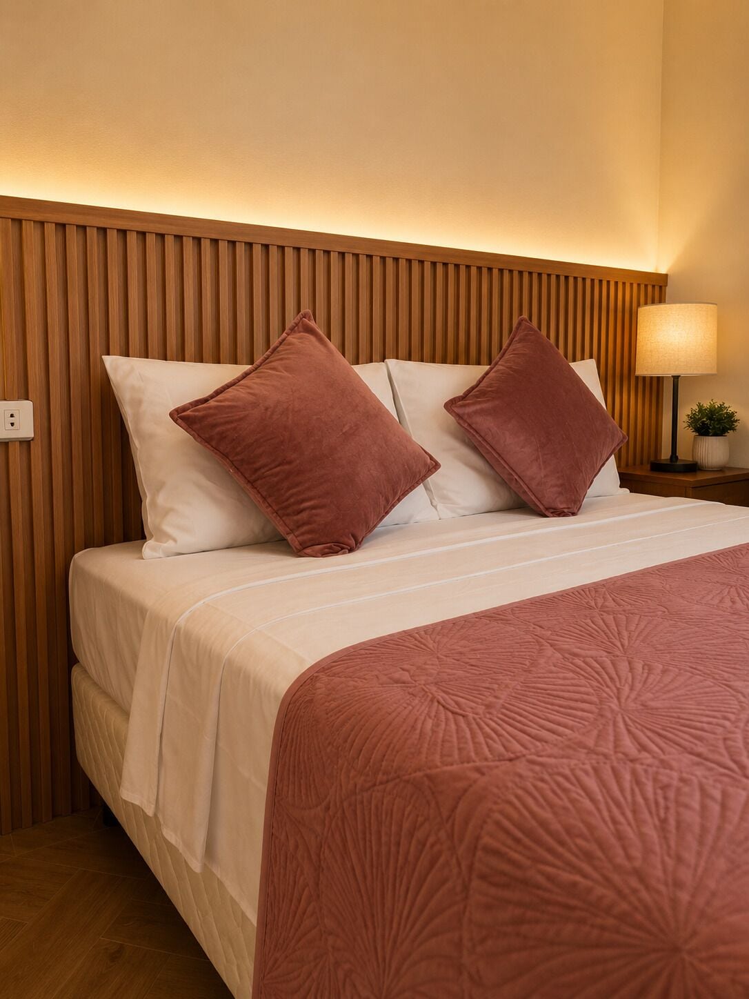 A neatly made bed with a white and pink bedspread, two pink pillows, and a wooden headboard.