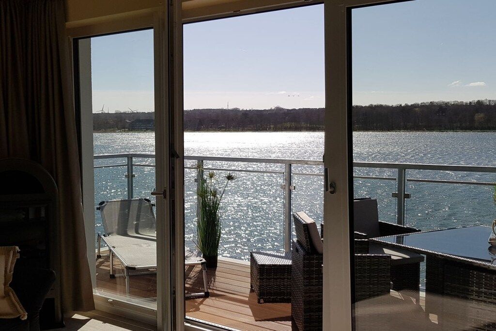 A deck with outdoor furniture, a potted plant, and a view of a body of water.