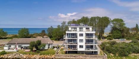 A multi-story building with balconies, situated by a body of water, likely a lake or river.