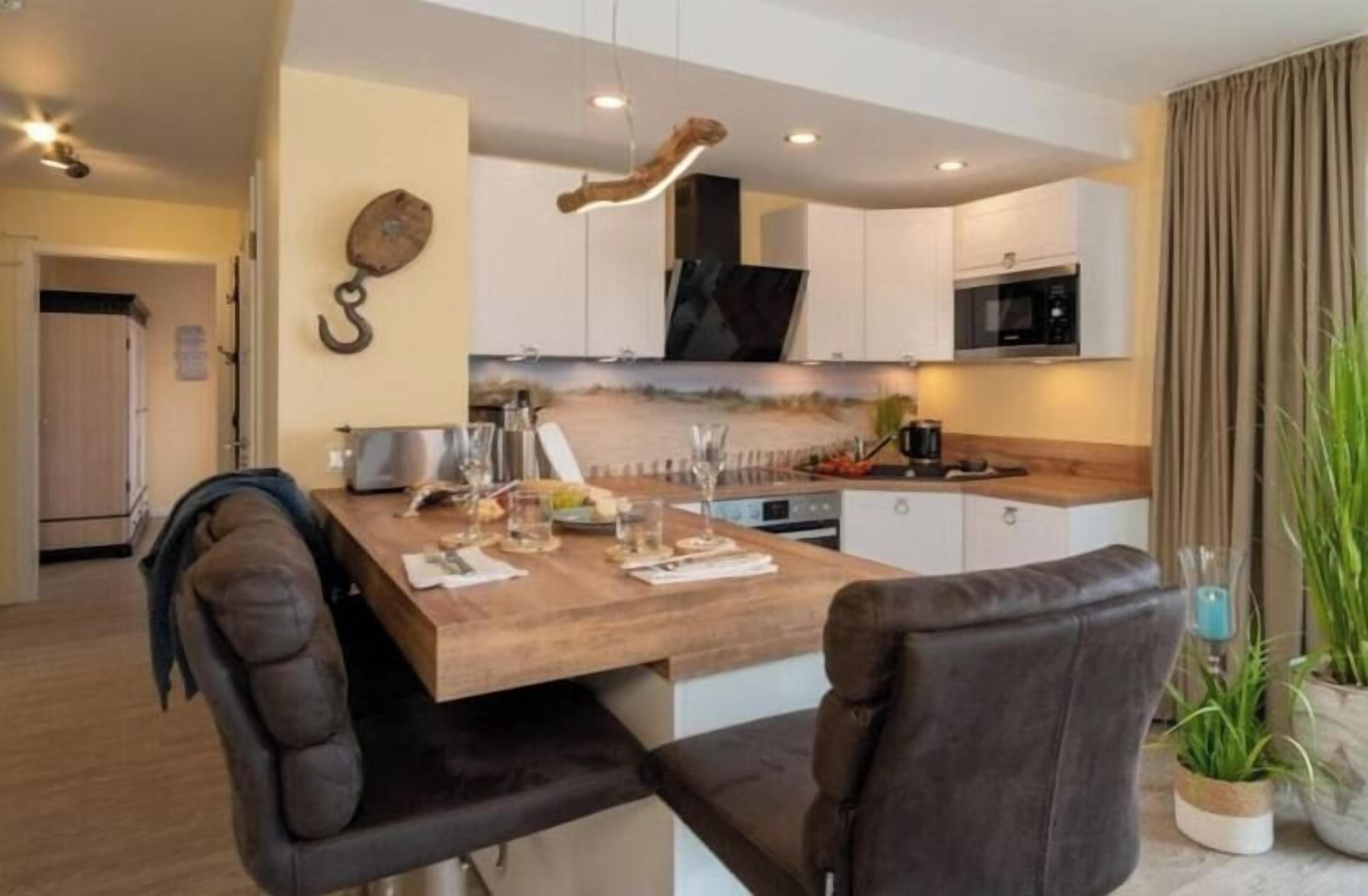 Une cuisine moderne avec un îlot central en bois, des armoires blanches et un luminaire suspendu.