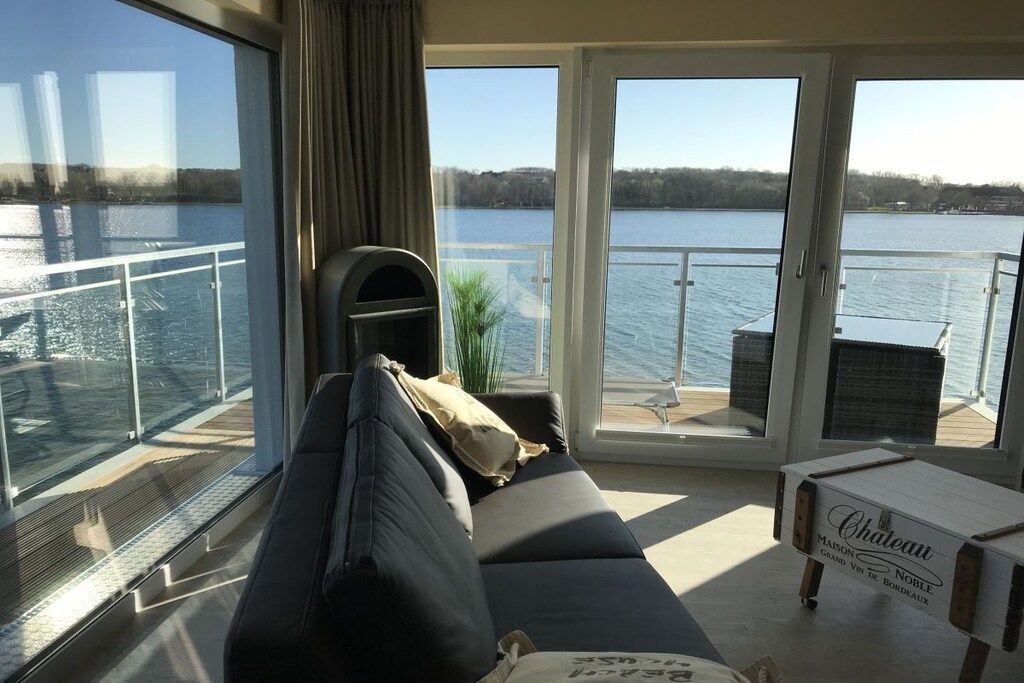 Ein Zimmer mit großem Fenster mit Blick auf ein Gewässer, einem Sofa, einem kleinen Tisch und einem Schild mit der Aufschrift 'Chateau'.