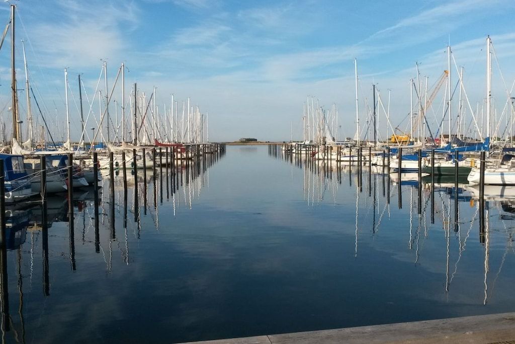 Un port de plaisance avec des bateaux amarrés à des quais en bois, une eau calme et un ciel dégagé.