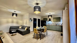 En moderne stue med sofa, spisebord, stole og hængende lamper.