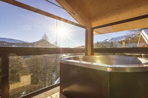 Ein modernes Interieur mit einem großen Glasfenster, einer Holzbalkendecke und einer Metallbadewanne.