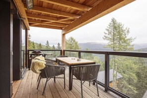 Une terrasse en bois avec une table et des chaises, donnant sur un paysage boisé.