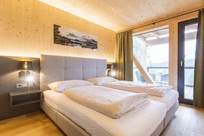 Ein Schlafzimmer mit zwei Betten, Holzwänden, einem Gemälde und Blick durch eine Glastür.